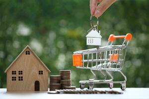 huis voor verkoop,model huis en miniatuur boodschappen doen kar Aan natuurlijk groen achtergrond, bedrijf investering en echt landgoed concept foto