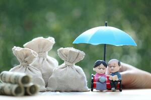 beleggingsfonds, liefdespaar senior en hand met de paraplu met stapel munten geld op natuurlijke groene achtergrond, bespaar geld voor voorbereiding in de toekomst en pensioen pensioen concept foto