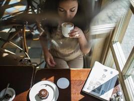 aantrekkelijk meisje met krullend haar zit in een café en drinkt koffie foto