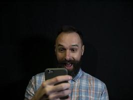 man met een baard kijkt in een mobiele telefoon foto