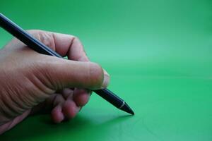 een zwart stylus pen wezen gehouden over- een groen achtergrond. foto