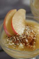 appel mousse met hennep zaden en appel plakjes in een glas foto