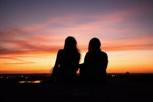 twee Dames genieten van een pittoreske zonsondergang van een heuveltop foto