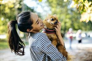 gelukkig jong vrouw Holding hond in een park foto