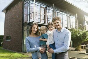 portret van glimlachen familie in voorkant van hun huis foto