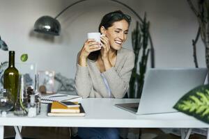 gelukkig jong vrouw Bij huis met laptop Aan bureau foto