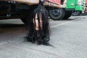 griezelig pop met lang haar- hangende van de voorkant bumper van de vrachtauto foto