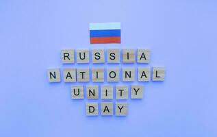 november 4, nationaal eenheid dag van Rusland, de vlag van Rusland, een minimalistisch banier met een opschrift in houten brieven Aan een blauw achtergrond foto