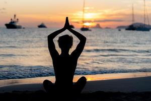 silhouet van fitnessmodel dat yoga doet bij zonsondergang