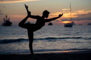 silhouet van fitnessmodel dat yoga doet bij zonsondergang foto