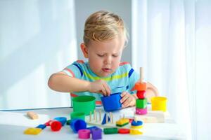 weinig jongen 2 jaren oud is gespeeld met een kleuren speelgoed. leerzaam logica speelgoed voor kinderen. montessori spellen voor kind ontwikkeling. foto