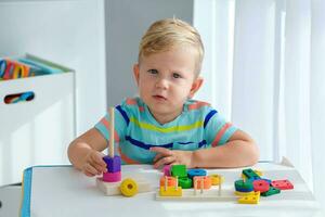 weinig jongen 2 jaren oud is gespeeld met een houten piramide. leerzaam logica speelgoed voor kinderen. montessori spellen voor kind ontwikkeling. foto