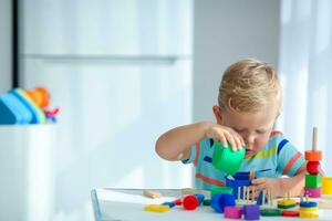 weinig jongen 2 jaren oud is gespeeld met een kleuren speelgoed. leerzaam logica speelgoed voor kinderen. montessori spellen voor kind ontwikkeling. foto