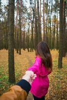 meisje in een roze regenjas houdt haar vriendje's hand- in de herfst Woud foto