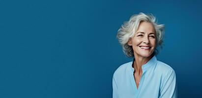 55 jaar oud glimlachen vrouw met grijs haar- Aan een blauw banier achtergrond met kopiëren ruimte. ai generatief foto