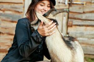 lachend boerderij meisje knuffelen een gehoornd geit foto