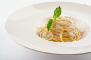 spaghetti met wit room saus Aan wit bord foto