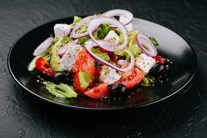 Grieks salade in zwart kom Aan steen foto