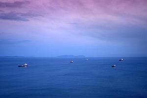 zeegezicht met schepen onder een roze zonsondergang