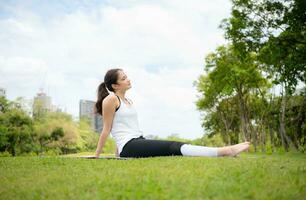 jong vrouw met buitenshuis activiteiten in de stad park, yoga is haar gekozen werkzaamheid. foto