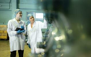 beide van vrouw kwaliteit controle arbeiders in een drinken water fabriek inspecteren de kwaliteit van water tanks voordat importeren de drinken water riem in de tank foto