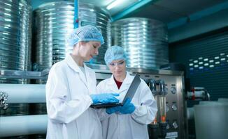 twee jong vrouw wetenschappers werken met tablet computer in drinken water fabriek foto