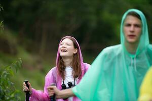 groep van vrienden in regenjassen wandelen Aan de Woud pad, wandelen concept. foto