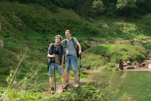 twee Mens wandelen in de Woud met rugzakken en trekking polen foto