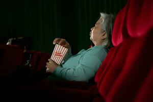 Aziatisch senior vrouw aan het kijken film Bij de bioscoop in de avond tijd. foto