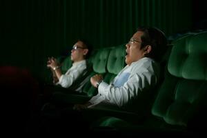 jong paar aan het kijken film in bioscoop, zittend Aan de groen stoelen. foto