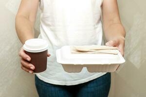 vrouw handen Holding een lunchbox en een glas van koffie foto