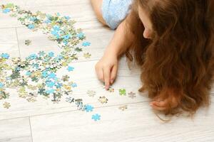 meisje verzamelt een puzzel van klein stukken foto