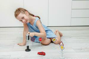 schattig weinig meisje spelen Bij huis Aan de verdieping met een schrijfmachine, weg tekens en verkeer lichten foto