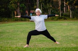 prettige vrouw in hijab en sportkleding die yoga doet en zich uitstrekt. foto