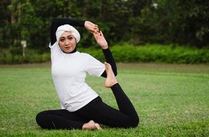 prettige vrouw in hijab en sportkleding die yoga doet en zich uitstrekt. foto