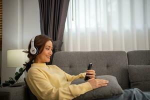 vrouw vervelend hoofdtelefoons en luisteren naar muziek- en het zingen gelukkig Bij huis Aan vakantie. foto