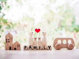 houten figuur van de familie staand Aan houten blokken met de woord familie, houten speelgoed- auto en miniatuur huis voor gelukkig familie concept foto