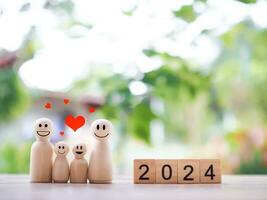 houten figuur familie gelukkig gezicht met hart en houten blok met aantal 2024. de concept van romantisch gevoelens, familie relatie. foto