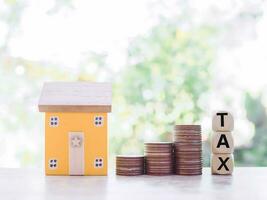 miniatuur huis, houten blokken met de woord belasting en stack van munten. de concept van betalen belasting voor huis en eigendom investering, huis hypotheek, echt beste. foto