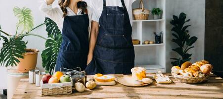 gelukkig jong volwassen paar maken ontbijt en drinken koffie samen in knus huis keuken in ochtend- Bij huis. voorbereidingen treffen maaltijd en lachend. levensstijl, vrije tijd en liefde concept. foto