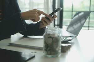 besparing geld en accounting concept. bedrijf Mens zetten munt insert naar pot en maken boekhouden boek voor financiën beheer naar investering en besparing. foto