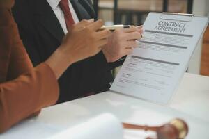 zaken en advocaten bespreken contractpapieren met koperen schaal op bureau in kantoor. wet, juridische diensten, advies, rechtvaardigheid en wet concept foto met film grain effect