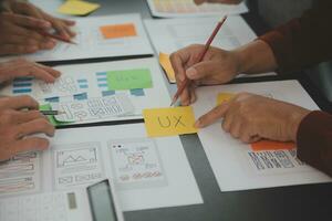 dichtbij omhoog ux ontwikkelaar en ui ontwerper brainstorming over mobiel app koppel wireframe ontwerp Aan tafel met klant breif en kleur code Bij modern kantoor.creatief digitaal ontwikkeling agentschap foto