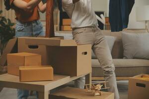 mooi jong paar in liefde hebben pret uitpakken dingen van karton dozen terwijl in beweging in samen in hun nieuw appartement foto