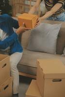mooi jong paar in liefde hebben pret uitpakken dingen van karton dozen terwijl in beweging in samen in hun nieuw appartement foto