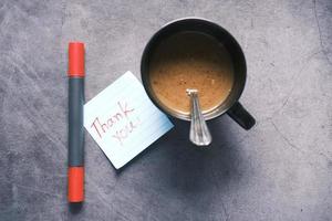 bedankbericht op kleverige nota en een koffiemok op tafel foto