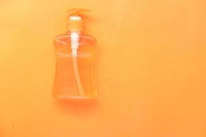 handwasvloeistof in een container op oranje achtergrond foto