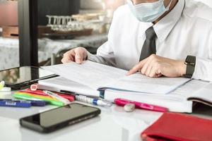 Aziatische onderwijsman die boeken leest, dus op zoek naar tablet foto