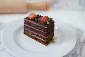 stuk van chocola taart met aardbeien en bitterkoekjes Aan wit bord foto