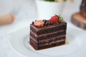 stuk van chocola taart met aardbeien en bitterkoekjes Aan wit bord foto